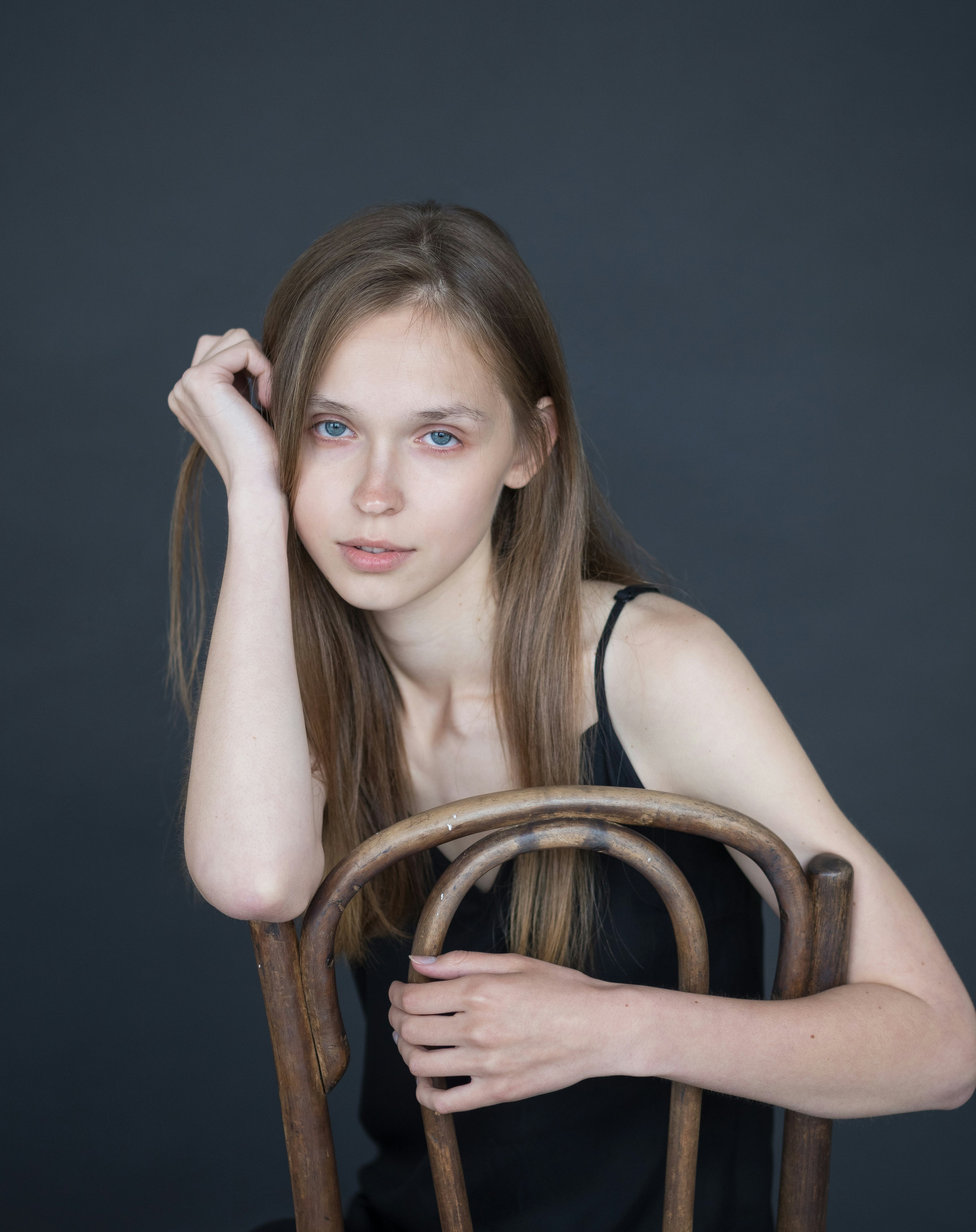 woman in black tank top sitting on brown wooden chair